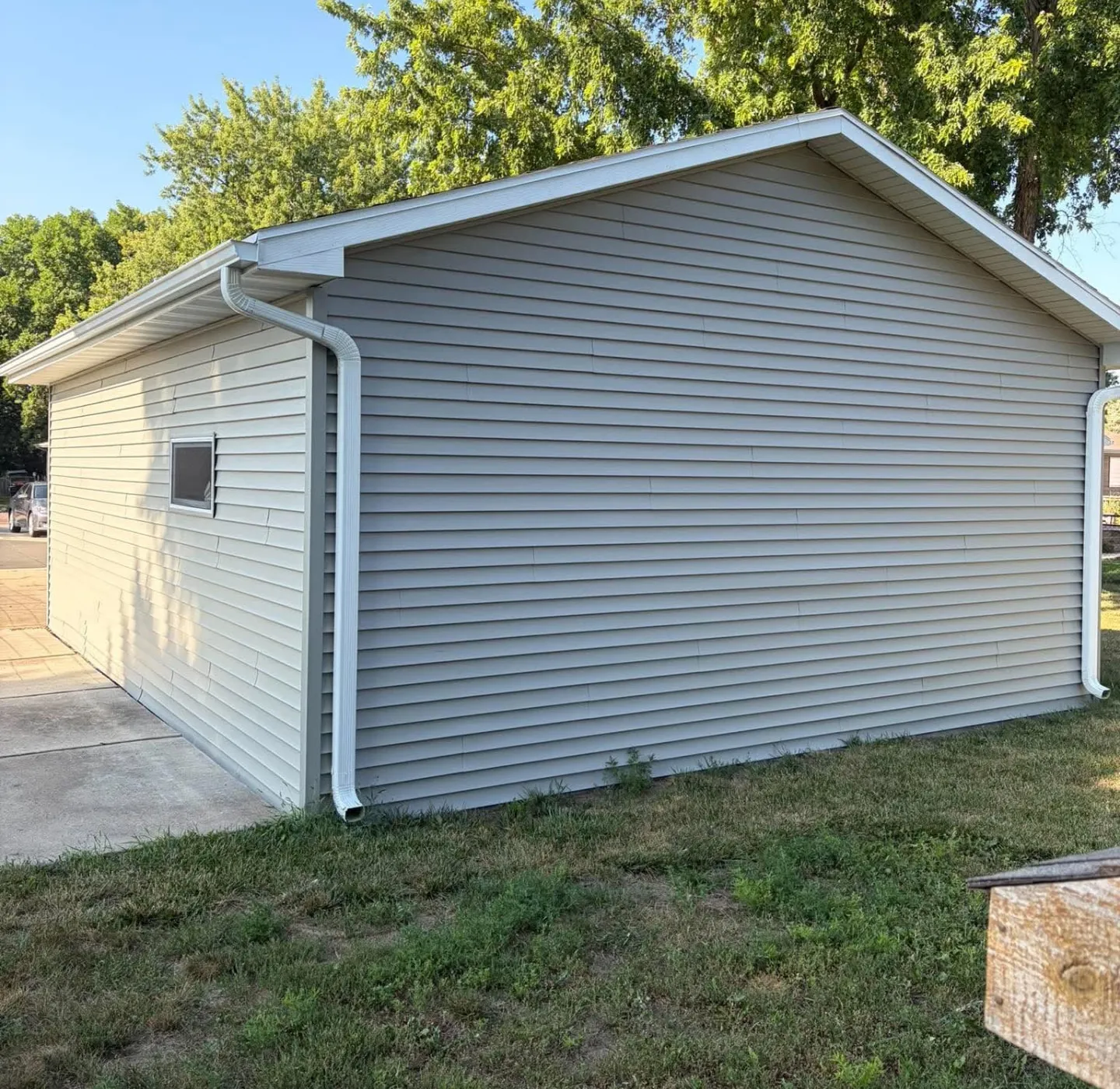 Detached garage with new light gray vinyl siding and white gutters