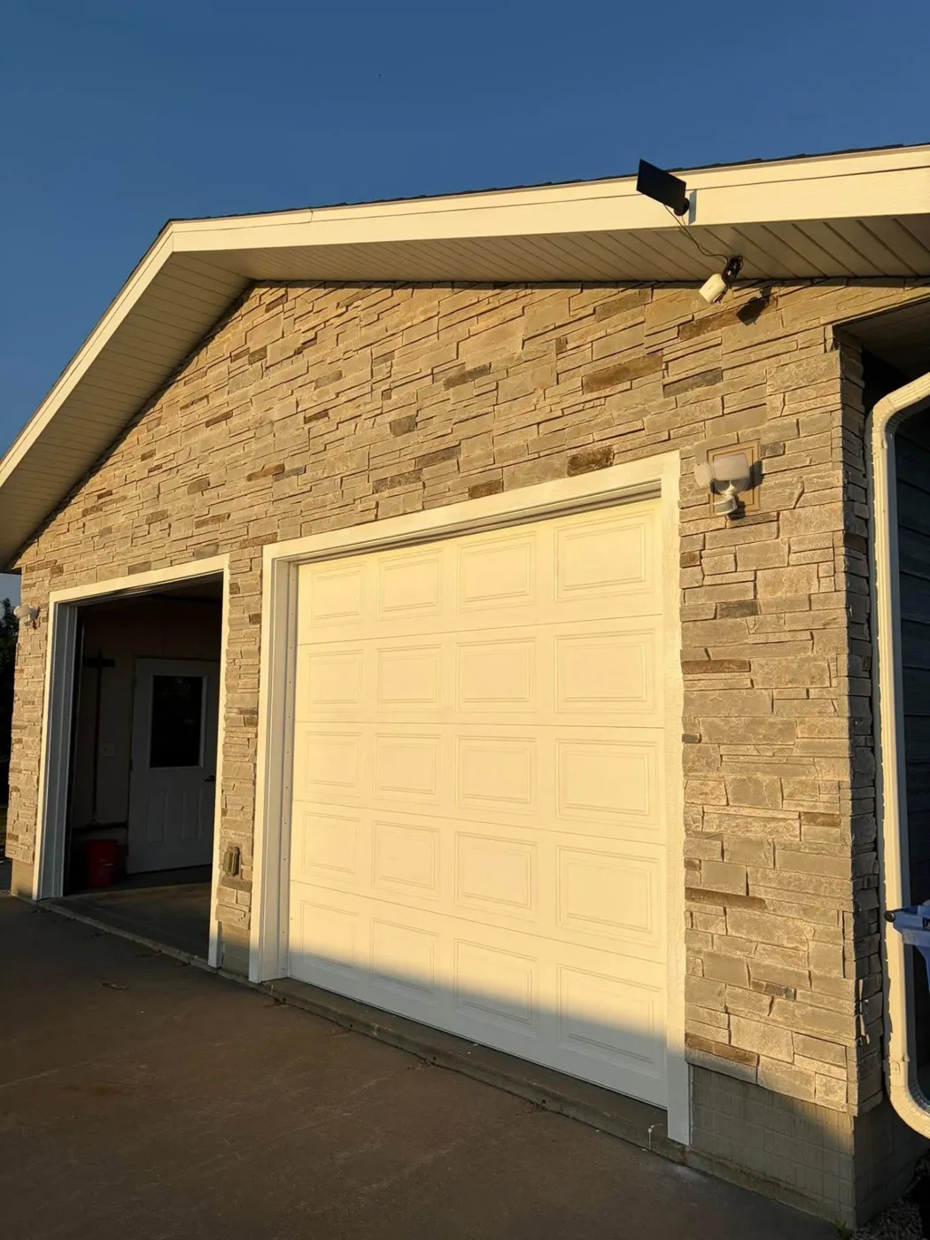 Garage with stacked stone exterior and white overhead door